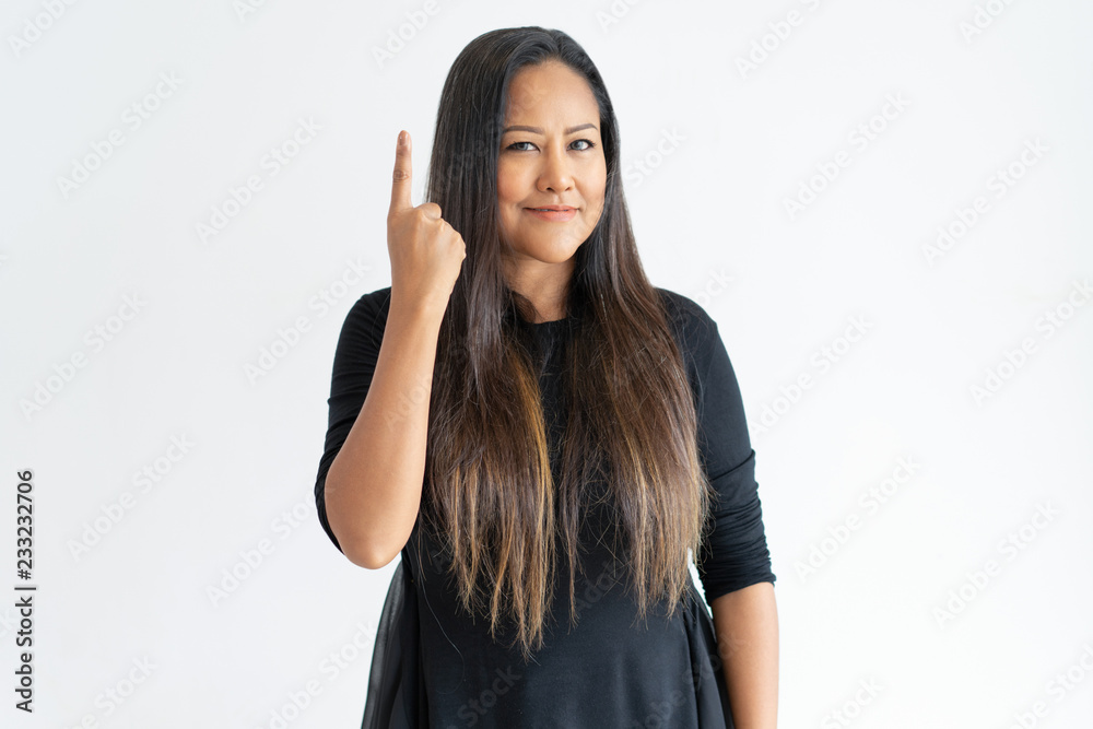Smiling middle-aged woman pointing upwards with forefinger. Lady looking at camera. Idea concept. Isolated front view on white background. Smiling middle-aged woman pointing upwards with forefinger. Lady looking at camera. Idea concept. Isolated front view on white background.