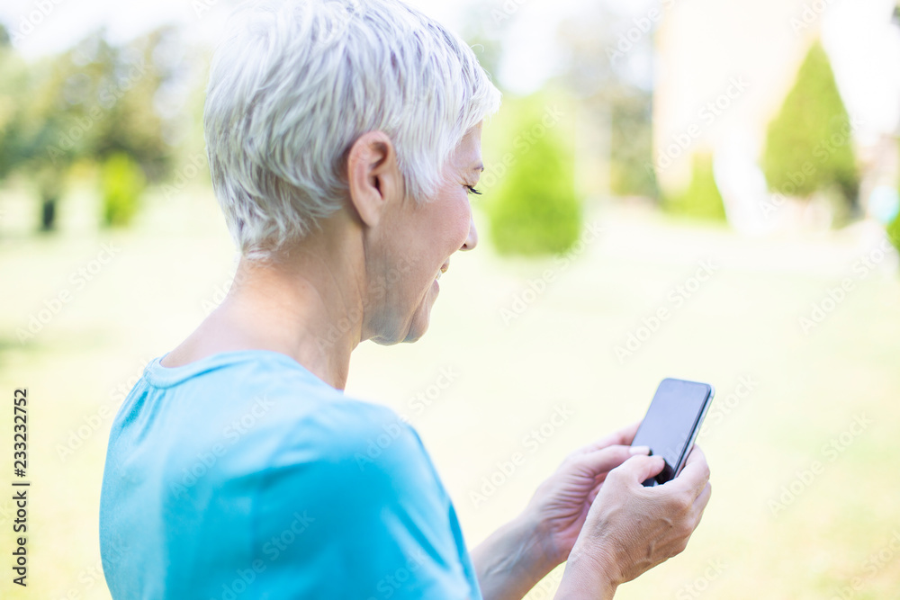 Senior woman in sports clothing  using smart phone outdoor