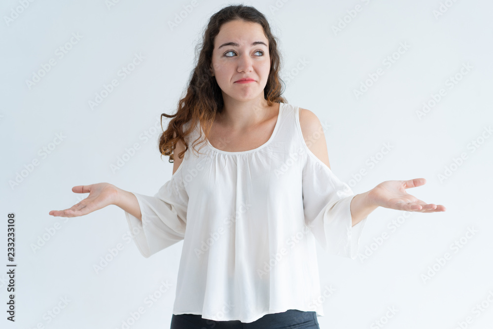 Portrait of confused young woman shrugging shoulders. Caucasian girl puzzled at difficult question. Problem or ignorance concept Portrait of confused young woman shrugging shoulders. Caucasian girl puzzled at difficult question. Problem or ignorance concept