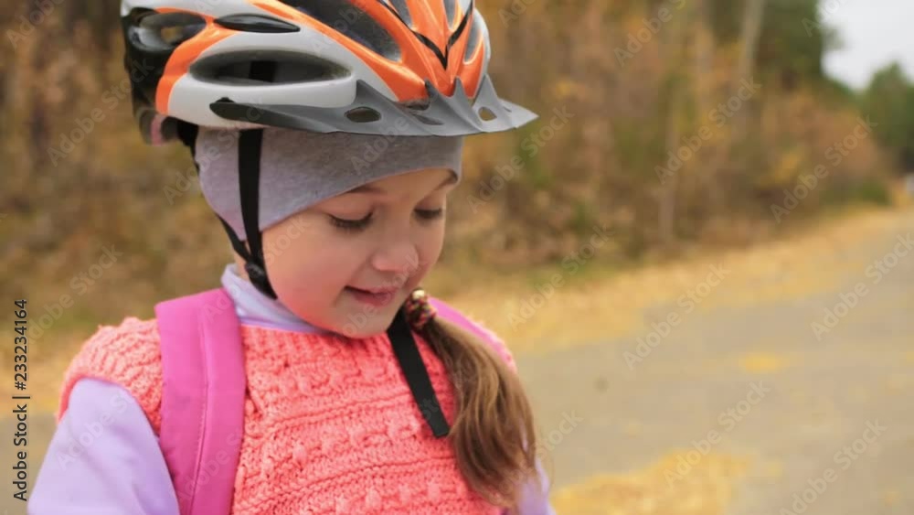 Kid drink water from an aluminum flask bottle. One caucasian children rides bike road in autumn park. Little girl riding black orange mtb cycle in forest. Biker motion ride with backpack and helmet. Kid drink water from an aluminum flask bottle. One caucasian children rides bike road in autumn park. Little girl riding black orange mtb cycle in forest. Biker motion ride with backpack and helmet.