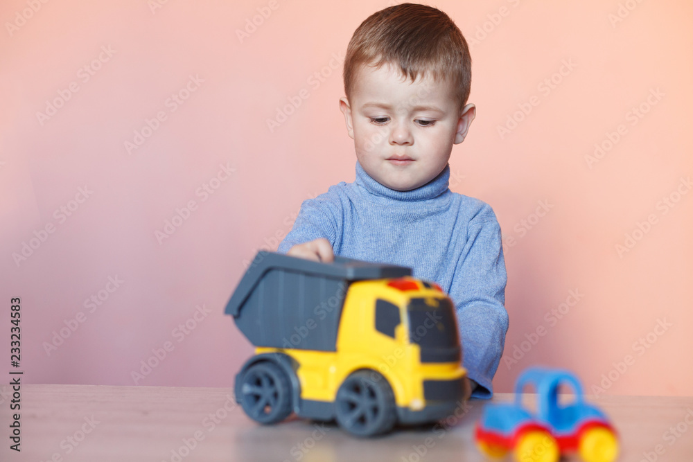 A cute little boy playing with model car collection. Toy mess in child room. A cute little boy playing with model car collection. Toy mess in child room.