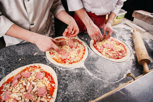 A dough for a pizza in the hands of the chef.