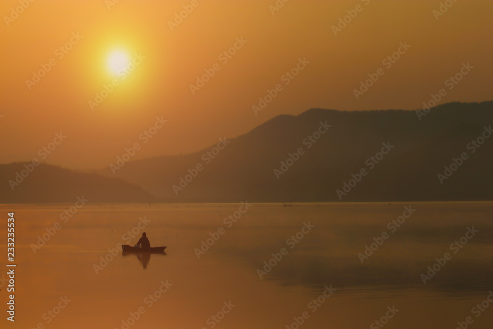 Silhouette Fishing man sitting on his boat with sunset sky and seclective focus, Background for travel or relax, Thailand