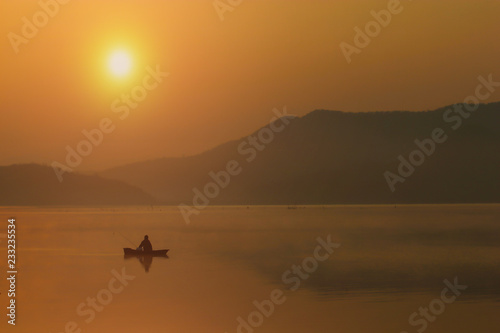 Silhouette Fishing man sitting on his boat with sunset sky and seclective focus, Background for travel or relax, Thailand