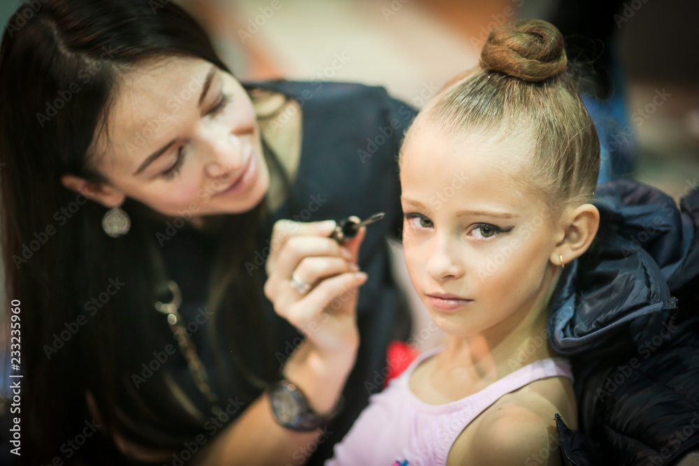 Mother making up to her daughter with cosmetics, blushes, eye shadows and brushes Mother making up to her daughter with cosmetics, blushes, eye shadows and brushes