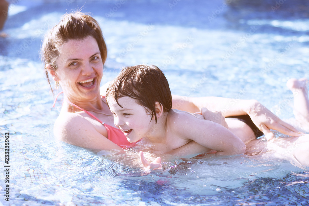Mom and son in swimming pool. Happy mother play with her son in the pool Mom and son in swimming pool. Happy mother play with her son in the pool