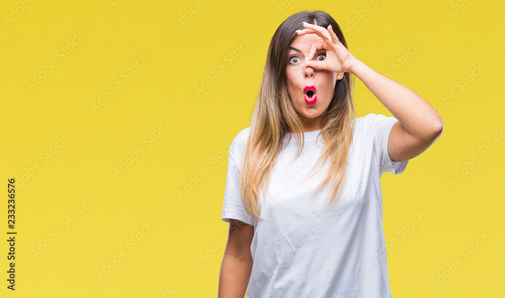 Young beautiful woman casual white t-shirt over isolated background doing ok gesture shocked with surprised face, eye looking through fingers. Unbelieving expression. Young beautiful woman casual white t-shirt over isolated background doing ok gesture shocked with surprised face, eye looking through fingers. Unbelieving expression.