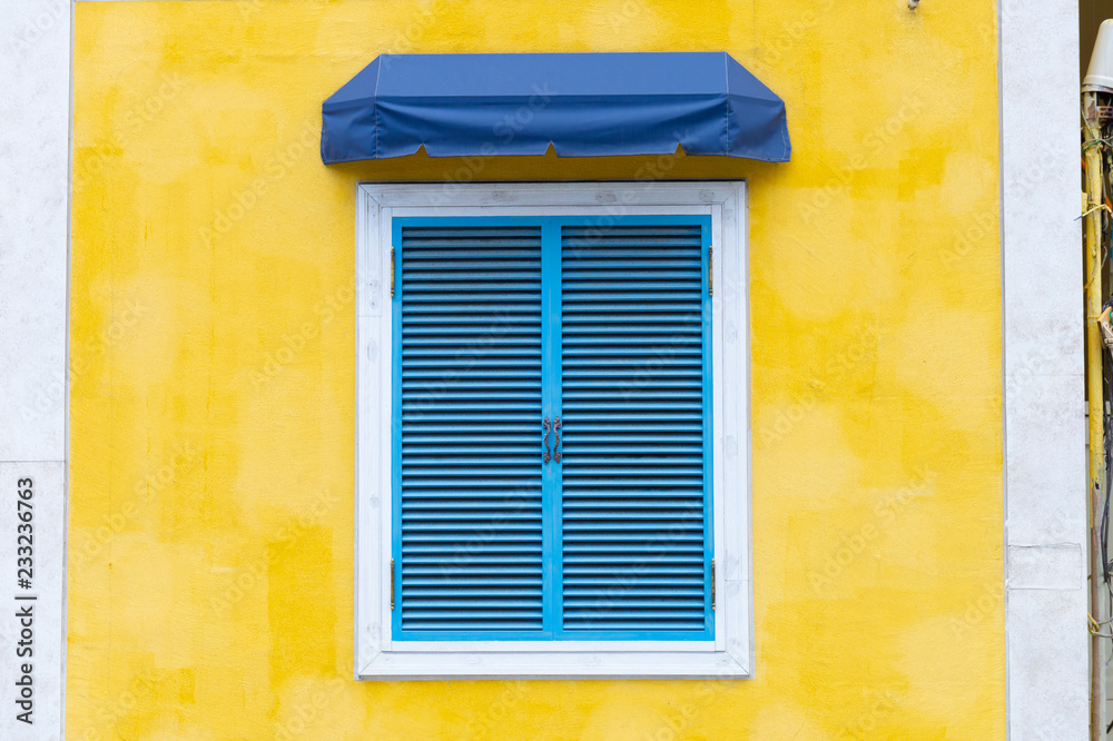 yellow wall of the house with a closed window and details.