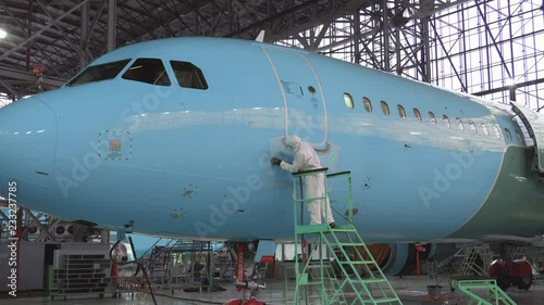 Painting the aircraft at the factory. The engineer repairing the aircraft. Maintenance of passenger aircraft. Repair of an aircraft wing. Passenger plane in the hangar in the repair. 4K
