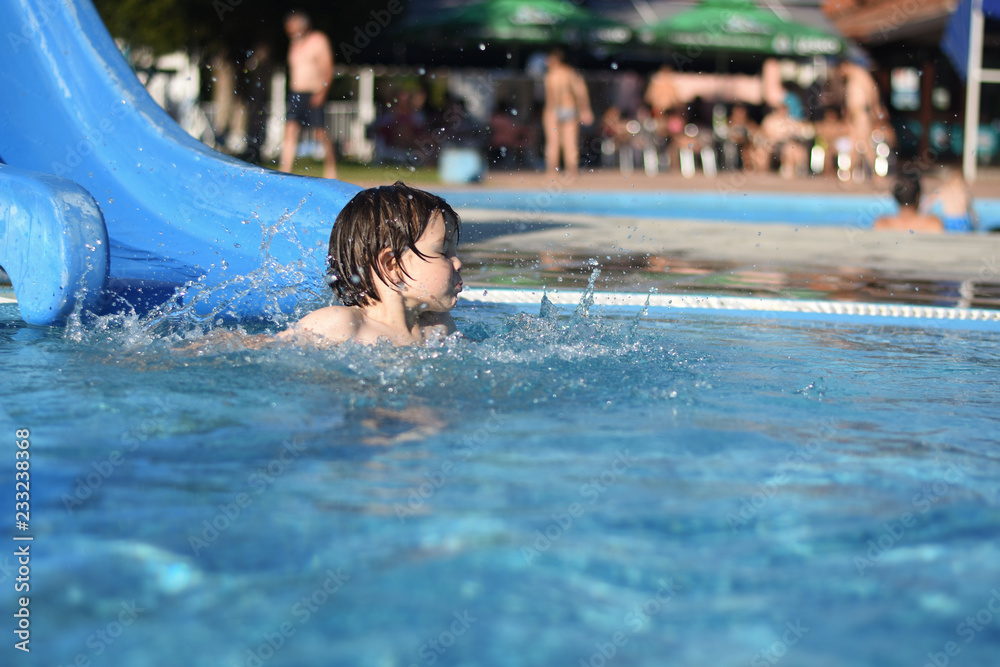 Little boy play swimming and playing in the pool. Cheerful child play in the swimming pool