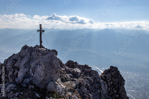 View over a mountain peak with a summit cross down to the Innvalley and Innsbruck in Austria in autumn as seen from a Via Ferrata called Innsbrucker Klettersteig, European Alps, Austria photo