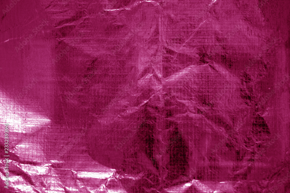 Crumpled transparent plastic  surface in pink color.