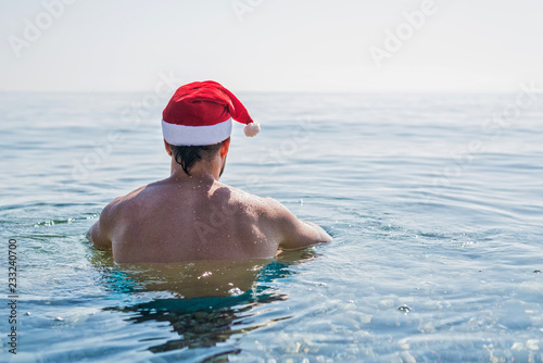 Man in Santa Claus hat on the beach, Christmas holidays. © mihakonceptcorn