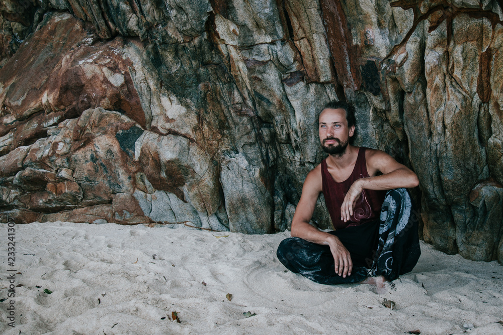 Crazy guy climbing on a rock and relaxing on the beach