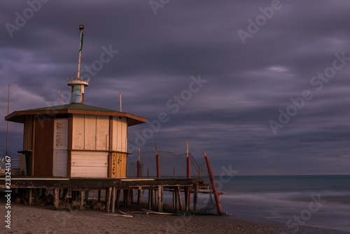 Sunset at the beach of Lido Di Ostia, the beach of Rome, Italy. Landscape of the lifeguard tower and beach during the sunset time. Low shutter speed shooting, with sea and beach. Rome, Italy