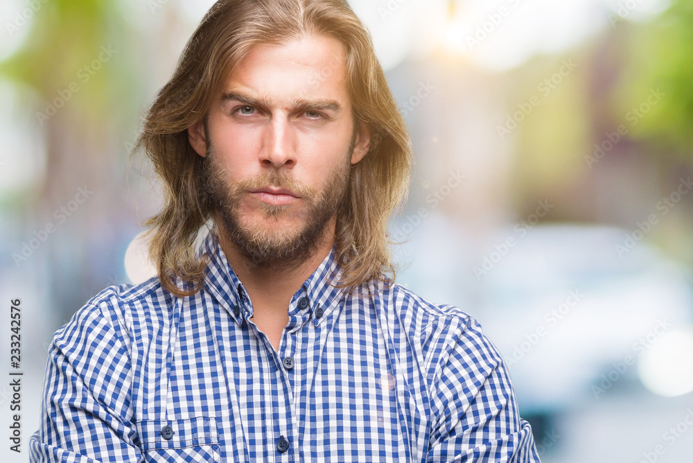 Young handsome man with long hair over isolated background skeptic and nervous, disapproving expression on face with crossed arms. Negative person. Young handsome man with long hair over isolated background skeptic and nervous, disapproving expression on face with crossed arms. Negative person.