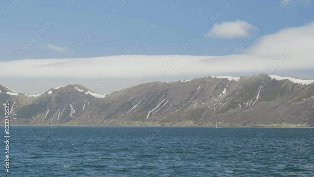 Sail yacht floating in blue sea on snowy mountains and bright sky landscape