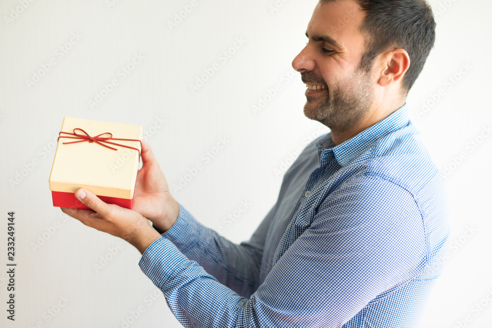 Happy handsome Hispanic man with stubble holding gift box and presenting it to you. Cheerful sales manager giving gift with purchase. Surprise concept Happy handsome Hispanic man with stubble holding gift box and presenting it to you. Cheerful sales manager giving gift with purchase. Surprise concept