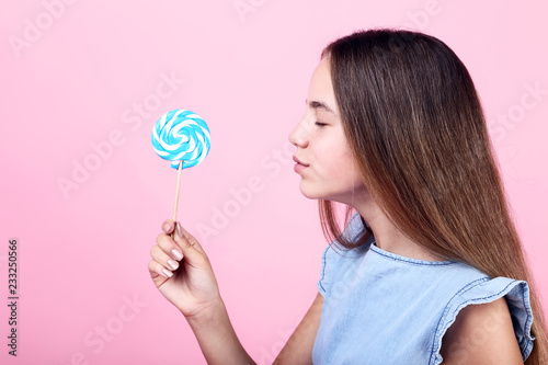 Young girl with lollipop on pink background