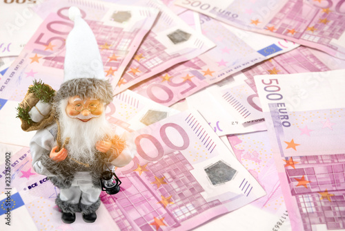 Eine Nikolaus Figur steht auf vielen Geldscheinen. Eine Überraschung wird durch Licht Flares angedeutet. Konzept eines plötzlichen Geld Geschenks zu Weihnachten. photo