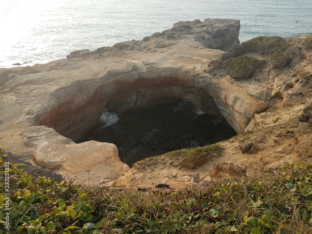 large hole in cliff at Oregon coast with ocean and waves
