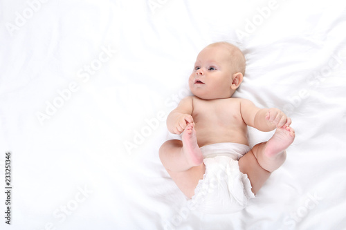 Little boy in diaper lying on white bed