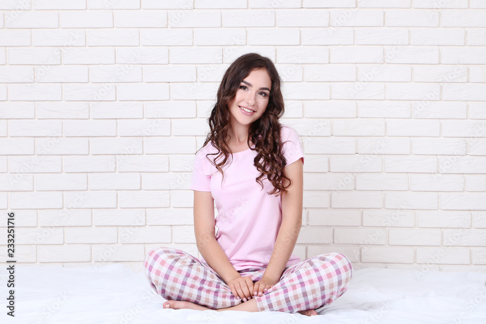 Beautiful girl in pajamas sitting on white bed Beautiful girl in pajamas sitting on white bed