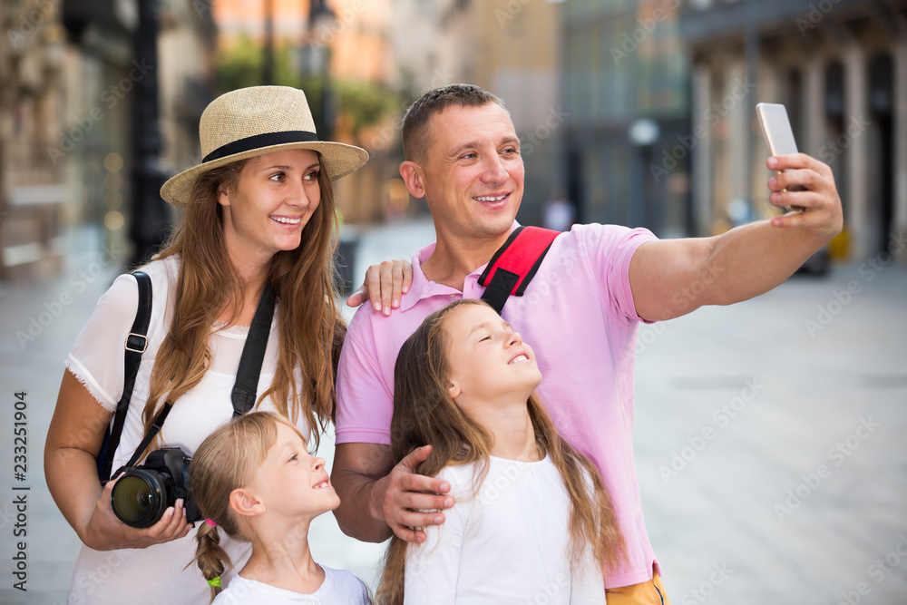 Joyful parents with two kids taking selfie