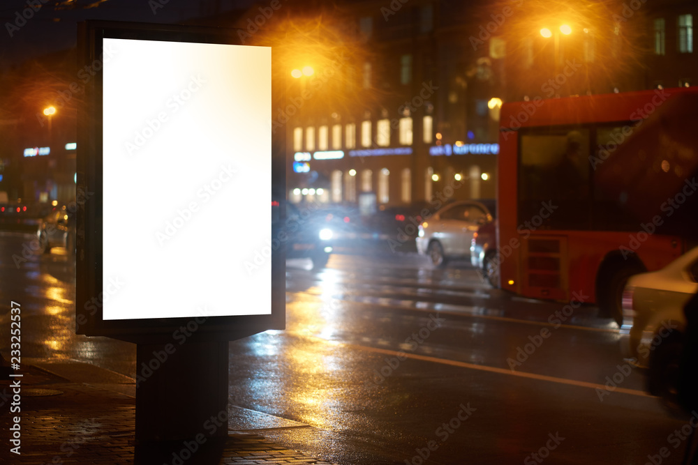 ad the billboard City format, shines in the night city. mockup with a white field for advertising. rainy evening, wet weather and road