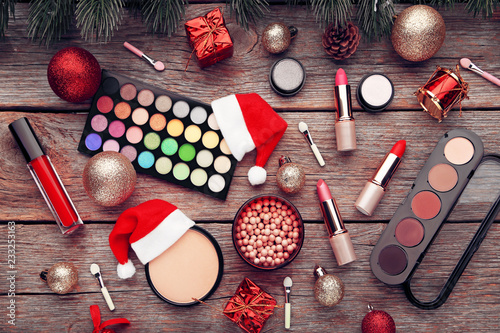 Makeup cosmetics with christmas baubles and santa hat on wooden table