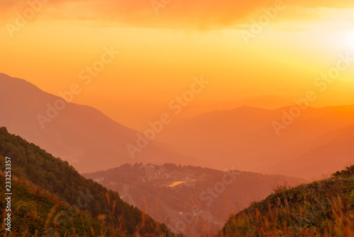 view of a beautiful mountain valley with a small town in the sunrise rays