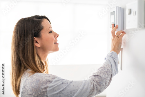 Fényképezés A woman set the thermostat at house