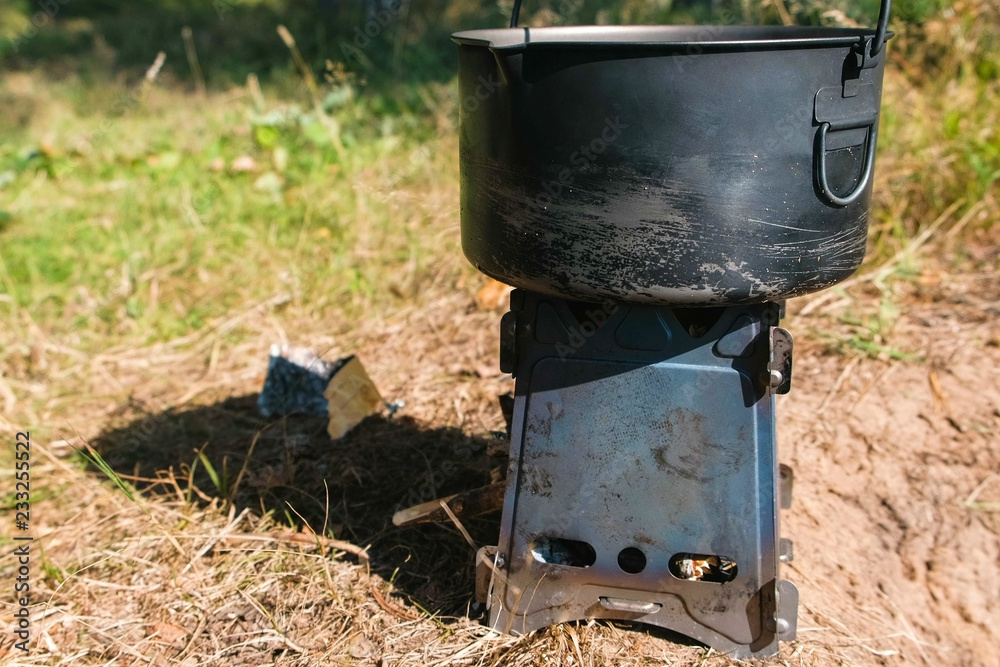 Pot on a metal camp furnace stove on woods outdoors. Pot on a metal camp furnace stove on woods outdoors.