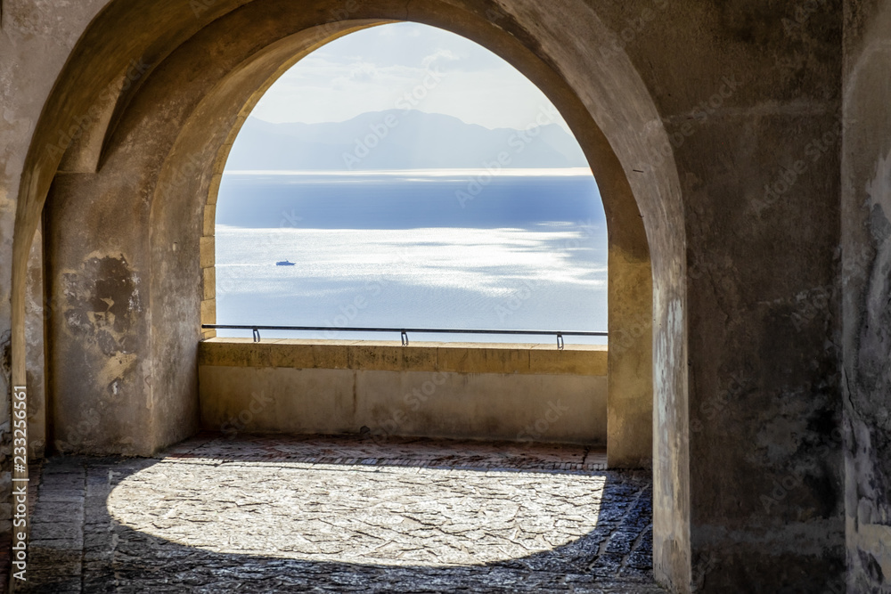 A beautiful view of the ocean through the arches of a balcony.