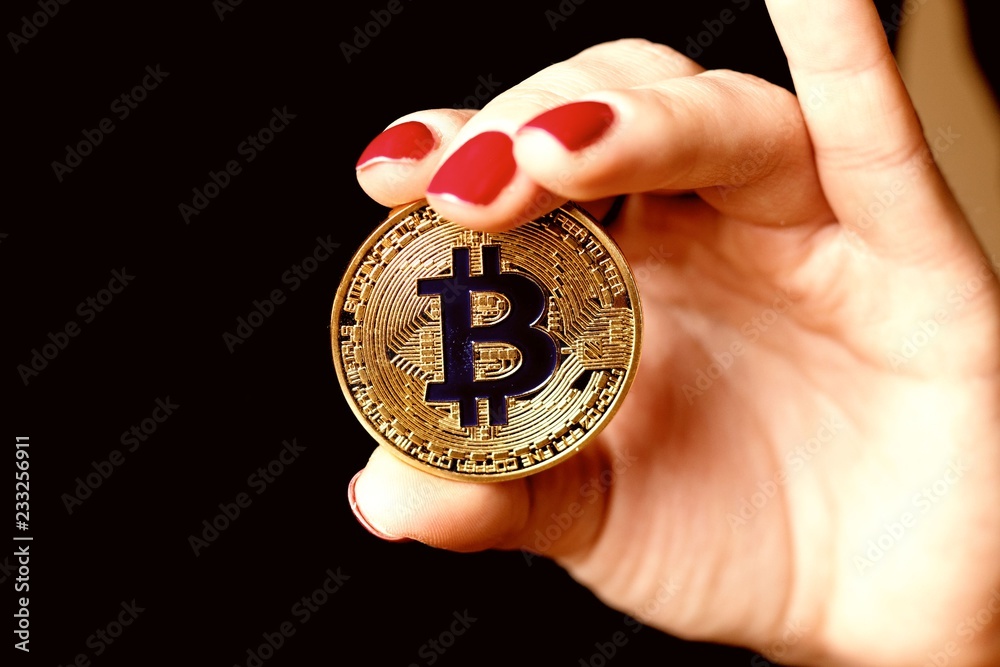 Woman's hand with red nails holding golden bitcoin Woman's hand with red nails holding golden bitcoin