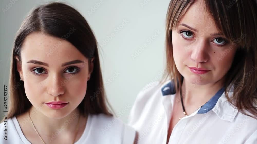 Look at camera beautiful young mother with her daughter other smile happy in studio white background attractive family female conversation cute girl face slow motion Look at camera beautiful young mother with her daughter other smile happy in studio white background attractive family female conversation cute girl face slow motion