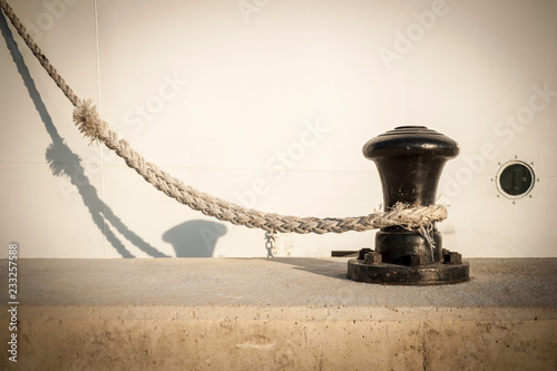 Bollard on a pier or quay, with mooring line from boat laided on it. photo