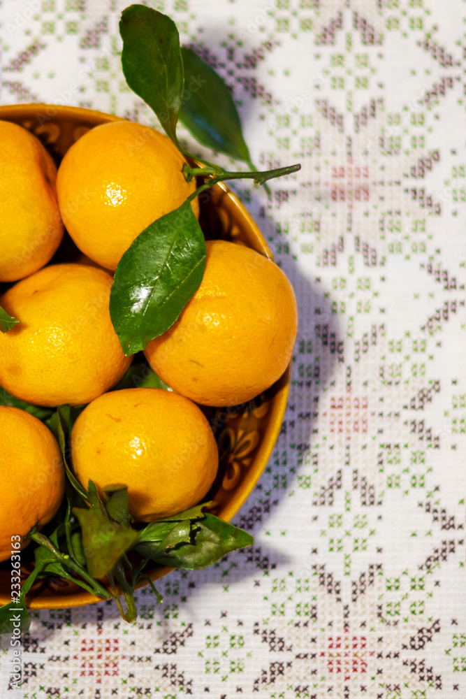 Tangerines (oranges, tangerines, clementines, citrus) with leaves in a ceramic plate