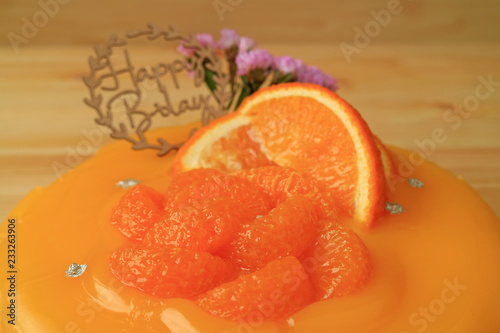 Closed Up Vibrant Color Delicious Mandarin Orange Birthday Cake on the Wooden Table 