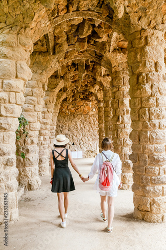 Photography Two happy traveler women tourists walking in famous Guell park in Barcelona