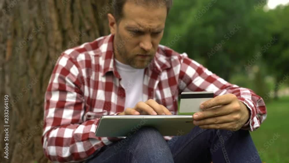 Man entering credit card number on tablet, paying online parking bills and fines Man entering credit card number on tablet, paying online parking bills and fines