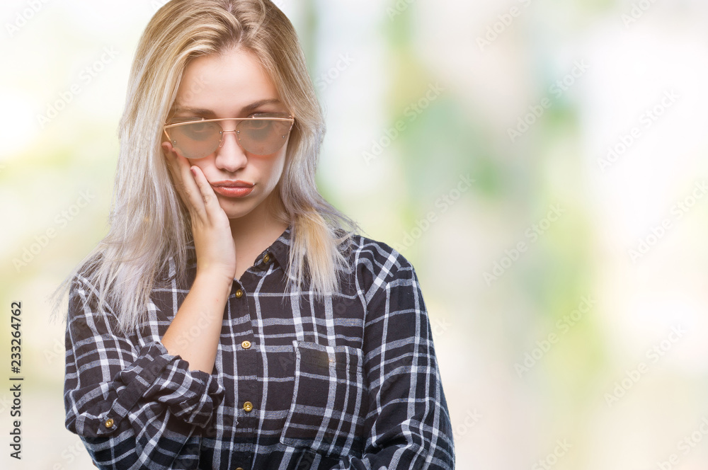 Young blonde woman wearing sunglasses over isolated background thinking looking tired and bored with depression problems with crossed arms. Young blonde woman wearing sunglasses over isolated background thinking looking tired and bored with depression problems with crossed arms.