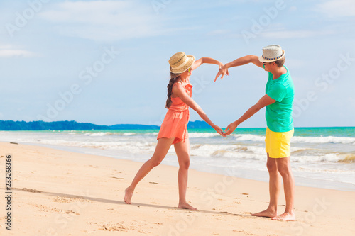 happy young couple in bright clothes making heart shape with their hands by the beach. Khao Lak, Thailand
