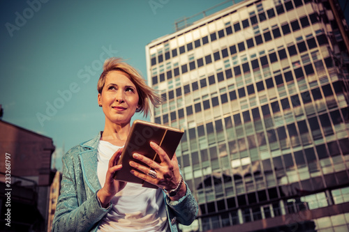 Elegant business woman uses a tablet in front of a office building
