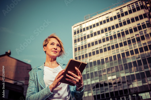 Photos Elegant business woman uses a tablet in front of a office building