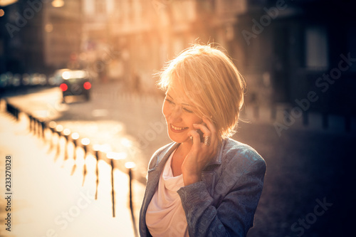 Confident mid-age woman talking on a cell phone in the street