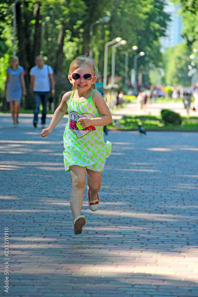 Happy little girl running in city park. Positive childish emitions Happy little girl running in city park. Positive childish emitions