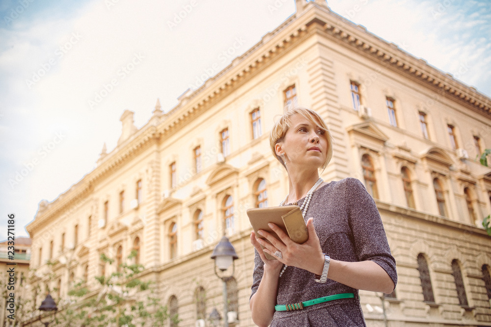 Elegant business woman uses a tablet in front of a office building