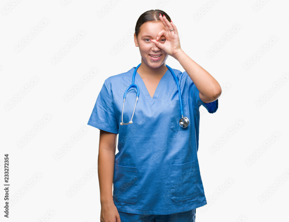 Young caucasian doctor woman wearing medical uniform over isolated background doing ok gesture with hand smiling, eye looking through fingers with happy face. Young caucasian doctor woman wearing medical uniform over isolated background doing ok gesture with hand smiling, eye looking through fingers with happy face.