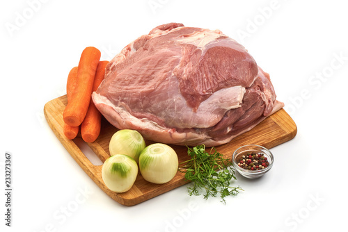 Uncooked ham or gammon with vegetables on a cutting board, isolated on a white background. Close-up.